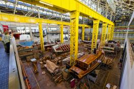 Estonian boatmaker invests over €1 million in production and product development. People looking down at wooden boats under construction in a large industrial shipyard
