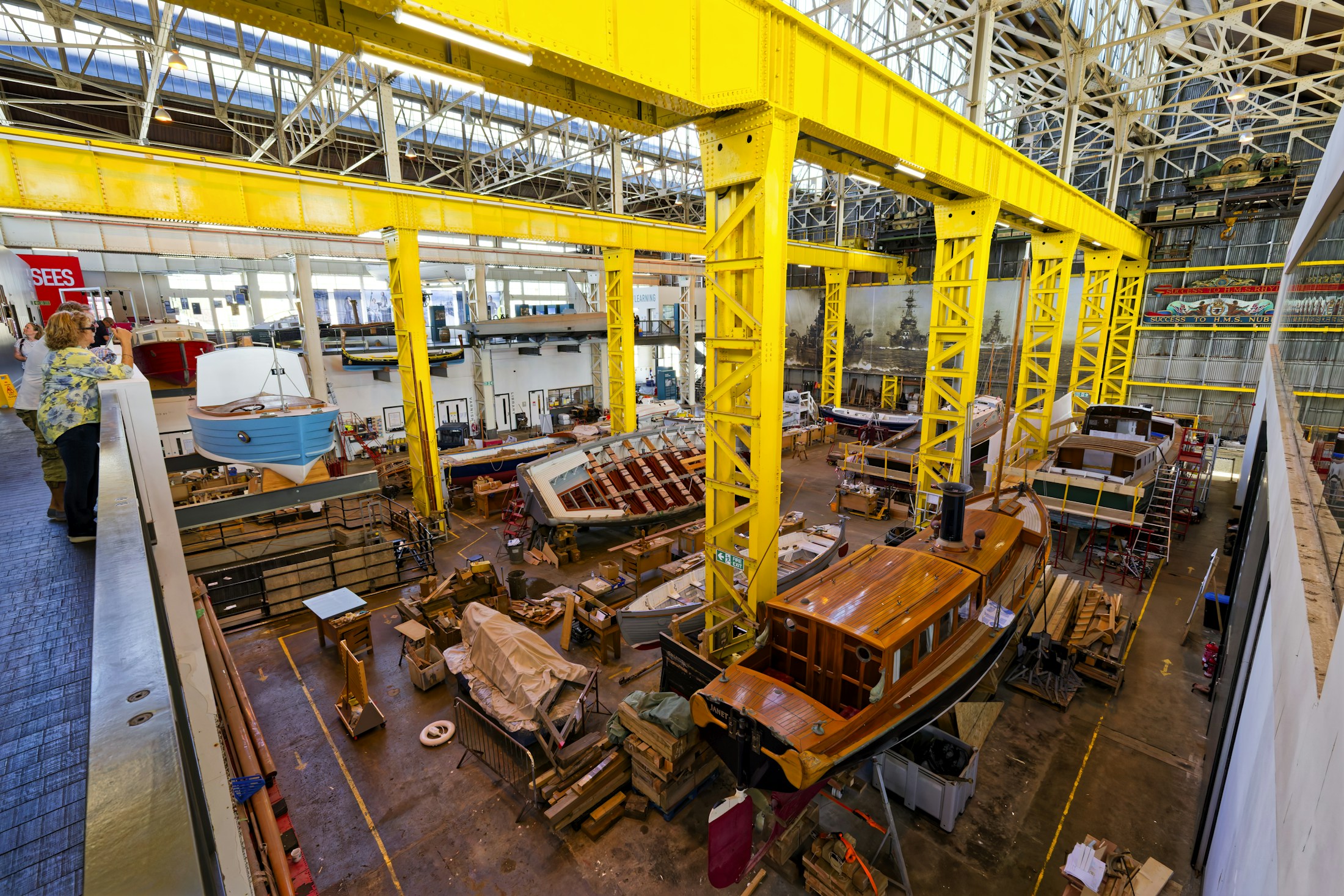Estonian boatmaker invests over €1 million in production and product development. People looking down at wooden boats under construction in a large industrial shipyard